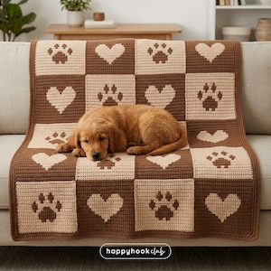 Puede incluir: Una manta de ganchillo marrón y beige con un patrón de corazones y huellas de patas. Un cachorro está acostado sobre la manta, que está sobre un sofá. Las palabras "happyhookclub" son visibles en la esquina inferior derecha.