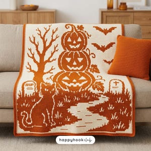 Peut inclure: Une couverture en crochet rectangulaire sur le thème d'Halloween avec une pile de trois citrouilles d'Halloween, un chat noir, un arbre dénudé, des pierres tombales et des chauves-souris en orange et crème. Le texte "happyhookclub" est imprimé en bas.