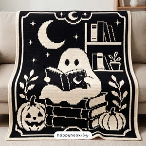 May include: A black and cream crochet blanket featuring a ghost reading a book while sitting on a stack of books. The design includes a crescent moon, stars, pumpkins, and a bookshelf. The text "happyhookclub" is printed at the bottom center.