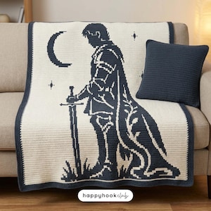 May include: A cream-coloured crochet blanket featuring a dark navy blue graphic of a knight standing with a sword, a crescent moon, and stars, accompanied by a matching solid dark navy blue square crochet pillow.