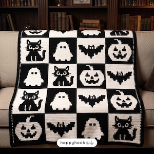 May include: A black and white crochet blanket featuring a repeating grid pattern of pixelated Halloween motifs including cats, ghosts, bats, and jack-o'-lanterns. A white label at the bottom center displays the text happyhookclub.