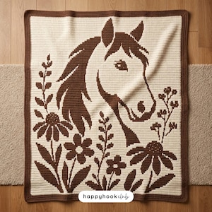 May include: A rectangular crochet blanket featuring a cream-coloured background with a dark brown horse head design surrounded by floral motifs. The blanket has a dark brown border and includes the text happyhookclub at the bottom centre.