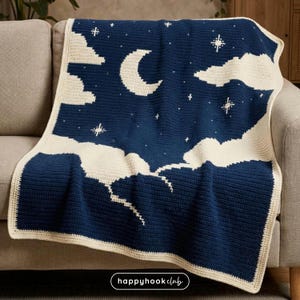 Könnte beinhalten: Eine marineblaue und cremefarbene Häkeldecke mit einem Nachthimmel-Design. Die Decke zeigt einen Halbmond, Sterne und Wolken. Die Decke ist über ein graues Sofa drapiert. Der Text "happyhook club" befindet sich unten.