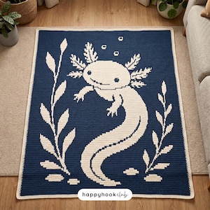 Könnte beinhalten: Eine rechteckige Häkeldecke mit dunkelblauem Hintergrund und einer großen, cremefarbenen Axolotl-Grafik in der Mitte. Das Design umfasst cremefarbene Wasserpflanzen auf beiden Seiten und kleine Blasen über dem Axolotl. Der Text "happyhookclub" ist unten mittig in Schwarz aufgedruckt.