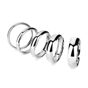 May include: A white ceramic mug with a black handle and the text "But First, Coffee" in a black, handwritten-style font. The mug is on a white surface.