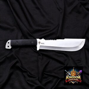 May include: A large, silver-colored knife with a black handle. The blade has a curved edge and a serrated spine. The handle is textured and secured with rivets. The knife has the text "M4X" and a skull logo.