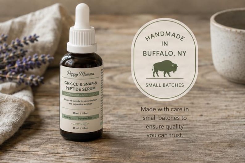 ​A product shot of an amber glass dropper bottle of Peppy Momma GHK-Cu & SNAP-8 Peptide Serum resting on a rustic wooden surface next to dried lavender. To the right of the bottle is an oval badge with a buffalo silhouette that reads "Handmade in Buffalo, NY, Small Batches." Below the badge, text reads, "Made with care in small batches to ensure quality you can trust."