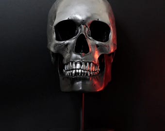 Terminus - Escultura de cráneo humano pintada a mano en negro y cromo con soporte de exhibición de madera y metal.