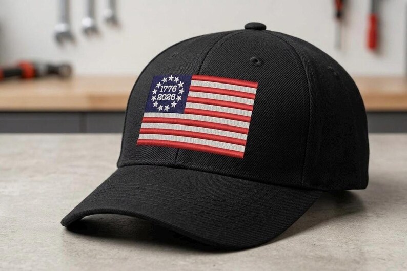 May include: Black baseball cap featuring an embroidered American flag design. The flag includes red and white stripes, a blue field with white stars, and the text "1776 2026".