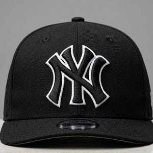 Könnte beinhalten: Schwarze Baseballkappe mit dem weißen NY-Logo. Die Kappe hat eine strukturierte Krone, einen gebogenen Schirm und einen verstellbaren Riemen. Das NY-Logo ist mit weißem Umriss gestickt. Ein klassisches Accessoire für Sportfans.