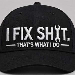 Könnte beinhalten: Eine schwarze Baseballkappe mit weißem Sticktext, der I FIX SHIT. THAT'S WHAT I DO. lautet. Der Buchstabe I im Wort SHIT ist durch ein weiß gesticktes Schraubenschlüsselsymbol ersetzt. Die Kappe hat eine strukturierte Krone und einen gebogenen Schirm.