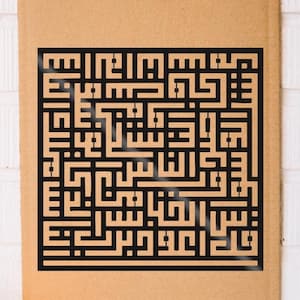 May include: A black, geometric design with Arabic calligraphy is displayed on a brown background. A lit purple candle and a decorative cupcake holder are in the foreground. The design is intricate and appears to be laser cut.