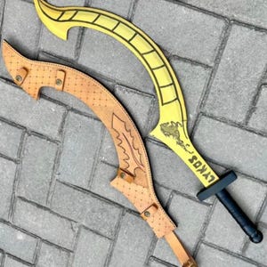 May include: A curved yellow blade with a black handle and the text LYKOS printed on the surface, accompanied by a tan leather sheath featuring a diamond-patterned texture, metal rivets, and a strap closure system for securing the blade.
