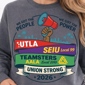 Labor movement PNG union strong workers rights protest design featuring a raised fist holding a red megaphone above a city skyline with palm trees, layered banners displaying UTLA SEIU Teamsters AALA and “Union Strong 2026” text, bold modern activist style with vibrant red, teal, green, and yellow colors, ideal for shirt sublimation, protest apparel, and digital download PNG file for union supporters and activists