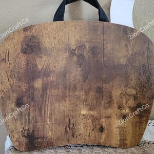 May include: A wooden lap desk with a black handle. The desk has a curved shape and a wood grain pattern in shades of brown and tan. The text "ZionCraftCo" is printed on the desk.