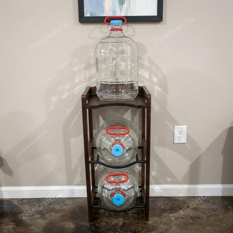 May include: A dark brown wooden storage rack with three levels, holding three large clear glass carboys. Each carboy features a red plastic handle and a light blue cap. The rack has a rectangular frame with open sides and a sturdy base.