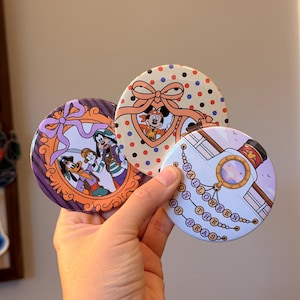 May include: Three circular pinback buttons featuring Disney characters. One shows Goofy and Max in pirate attire within an orange frame. Another displays Mickey Mouse in a heart-shaped frame with polka dots. The third depicts a ship with the text HALLOWEEN ON THE HIGH SEAS.