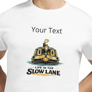 May include: White t-shirt featuring a colorful illustration of a boat with the text "LIFE IN THE SLOW LANE". The shirt also has the text "Your Text" above the boat graphic. The shirt is made of a soft, comfortable material.