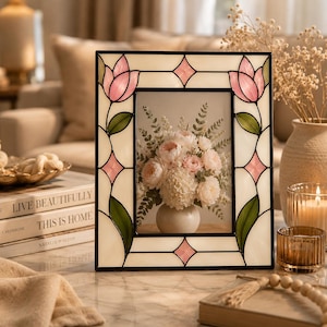 May include: A rectangular stained glass picture frame featuring a cream-colored background with pink tulip motifs at the top corners and green leaves along the sides. The frame includes small pink diamond-shaped accents and a black metal border.