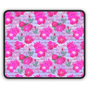 May include: A rectangular mousepad featuring a floral pattern of bright pink roses with green leaves and buds. The design includes faint, handwritten text on a light blue background, all framed by a black border.