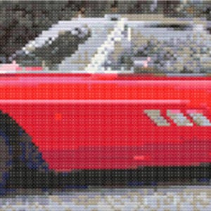 May include: A classic red vintage car with a silver trim and a white roof. The car has a sleek design with three silver accents on the side. The car is parked on a gray surface.