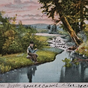 May include: Vintage postcard featuring a serene landscape with a river and lush greenery. A person is seated on the riverbank, fishing. The postcard has handwritten text in cursive, adding a personal touch. The sky has a soft, colorful gradient.