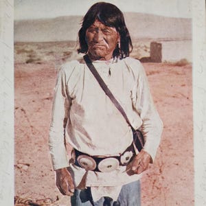 May include: A vintage postcard featuring a colorized photograph of an individual with dark hair wearing a light-colored long-sleeved shirt, dark trousers, and a wide belt with circular metal ornaments. The text 234. Old Moki Indian. is printed below.