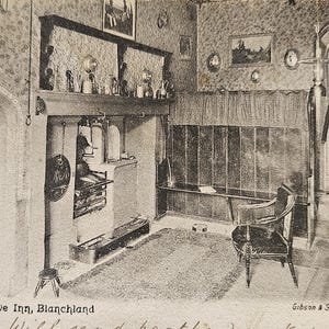 May include: A vintage black and white postcard showing the interior of the Kitchen, Lord Crewe Inn, Blanchland. The scene features a large stone fireplace, a wooden chair, and patterned wallpaper. Handwritten text at the bottom reads: Will send heather next week.