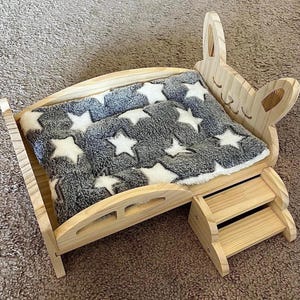 May include: A white ceramic mug with a black handle and the text "But First, Coffee" in a bold, black font. The mug is set against a blurred background, highlighting its clean design.