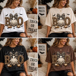 Op de afbeelding: Een collectie van vier T-shirts met korte mouwen in wit, beige, zwart en bruin. Elk shirt heeft een afbeelding van een geest met een strik met luipaardprint, omringd door het woord BOO in luipaardletters, kleine pompoenen en vleermuizen.