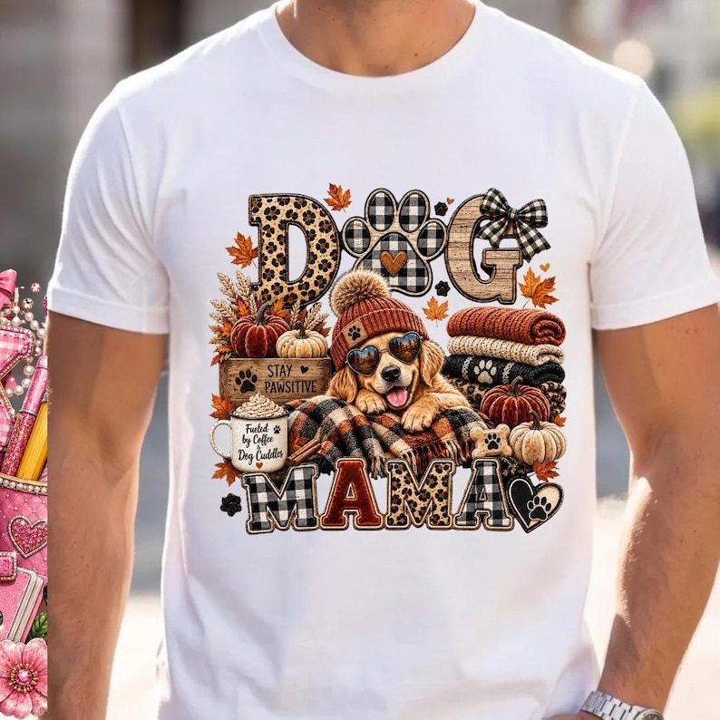 Puede incluir: Una camiseta blanca de manga corta con un gr&aacute;fico de un golden retriever con gorro y gafas de sol en forma de coraz&oacute;n. El dise&ntilde;o incluye el texto DOG MAMA, una taza de caf&eacute; con la inscripci&oacute;n Fueled by Coffee & Dog Cuddles, calabazas y hojas.