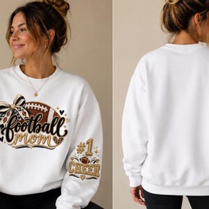 Peut inclure: Un sweat-shirt blanc &agrave; col rond avec un motif sur le devant repr&eacute;sentant un ballon de football marron, un n&oelig;ud &agrave; carreaux noir et blanc et le texte football mom. La manche gauche affiche le texte #1 CHEER avec un petit ballon en or et noir.