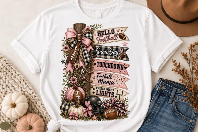 May include: A white t-shirt featuring a graphic print of a wooden post decorated with a pink and black plaid bow, pumpkins, a football helmet, and a pom-pom. The text reads: Hello Football, Game Day, TOUCHDOWN, Football Mama, and FRIDAY NIGHT LIGHTS.