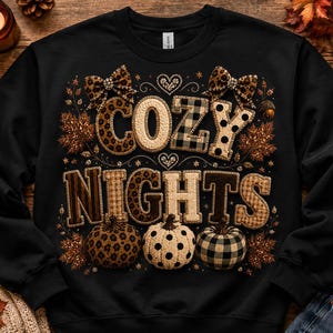 May include: A black crewneck sweatshirt featuring the text COZY NIGHTS in large, patterned block letters. The design includes leopard print, plaid, and polka dot motifs, accented with two leopard print bows, hearts, and three pumpkins.