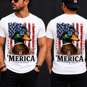 Peut inclure: Un t-shirt blanc avec un motif représentant un canard colvert portant une casquette et des lunettes de soleil aux motifs du drapeau américain. Le canard porte une chaîne dorée avec une plaque USA. Un drapeau américain vieilli et le texte 'MERICA.