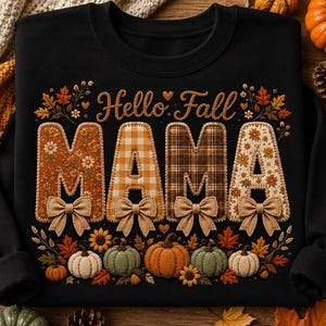 Puede incluir: Una sudadera negra de cuello redondo con el texto Hello Fall y MAMA en letras grandes. Las letras están rellenas con varios patrones temáticos de otoño, incluyendo diseños florales y de cuadros, cada uno con un pequeño lazo beige en la base.