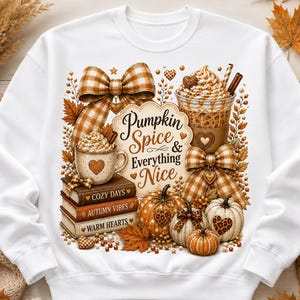 May include: A white sweatshirt featuring a graphic print of a stack of books labeled Cozy Days, Autumn Vibes, and Warm Hearts, topped with a mug of coffee, a plastic cup of iced coffee, pumpkins, and plaid bows with the text Pumpkin Spice & Everything Nice.
