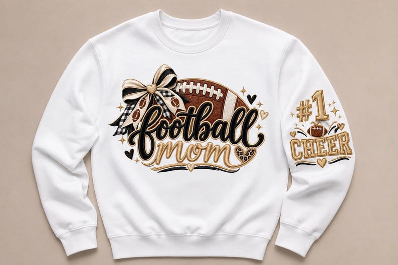 Peut inclure: Un sweat-shirt blanc &agrave; manches longues avec un motif graphique repr&eacute;sentant un ballon de football marron, un n&oelig;ud &agrave; carreaux noir et blanc et le texte football mom. La manche affiche le texte #1 CHEER avec un petit ballon et des d&eacute;tails dor&eacute;s.