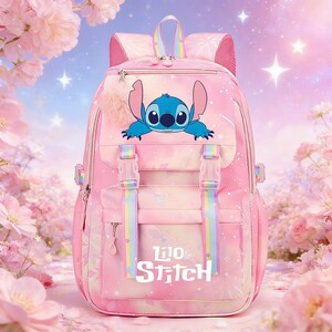 May include: Pink backpack featuring a blue cartoon character and the text "Lilo & Stitch." The backpack has rainbow-colored straps and a fluffy pink pom-pom. The background is a soft pink with floral and star accents.