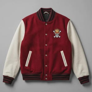 May include: A maroon varsity jacket with cream-colored sleeves, featuring a ribbed collar and cuffs with black stripes. The front has silver snap buttons, two welt pockets, and an embroidered skull and crossbones logo wearing a gold crown.
