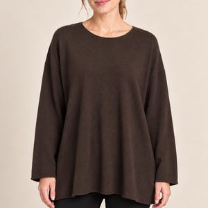 Könnte beinhalten: Ein dunkelbrauner Langarmpullover mit weiter, lockerer Passform und rundem Ausschnitt. Das Kleidungsstück zeichnet sich durch ein schlichtes, einfarbiges Design mit geraden Ärmeln und einem leicht ausgestellten Saum unter der Taille aus.