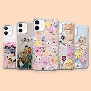May include: A selection of phone cases with diverse designs. One case has a pink background with cartoon animal faces. Another case displays a group of people. Other cases have cartoon characters and the text "Stray Kids".