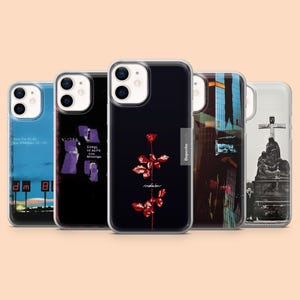 May include: Five clear phone cases, each with a unique design. The cases display album art, including a red rose on black, cityscapes, and text. These cases are designed to fit a smartphone, offering protection and style.