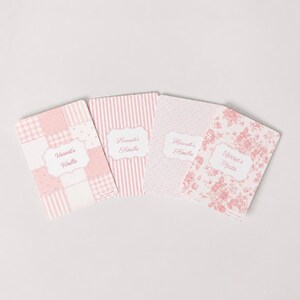 Puede incluir: Cuatro fundas rectangulares para Kindle en tonos rosa claro y blanco. Cada funda presenta una etiqueta blanca central con el texto Harriet's Kindle. Los diseños incluyen un patrón de patchwork, rayas verticales, puntos y flores.