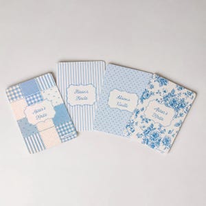 May include: Four rectangular Kindle skins featuring blue and white patterns. Each skin displays a central decorative label with the text Alison's Kindle. The designs include patchwork, vertical stripes, small polka dots, and a blue floral print.