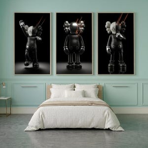 May include: Three framed wall art prints featuring a stylized black and white character with X-shaped eyes. Each print displays the figure in a different pose against a solid black background with thin, glowing orange lines radiating from the head.
