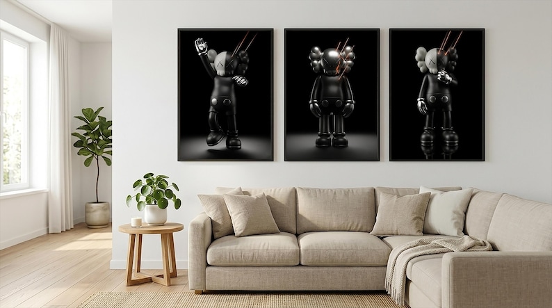 May include: Three framed wall art prints featuring black KAWS-style figures against a solid black background. Each figure has signature X-shaped eyes and is depicted with thin red laser-like lines extending from the head area in a dark setting.