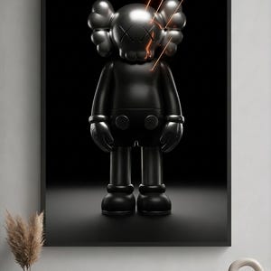 May include: A framed wall art print featuring a matte black KAWS-style character figure with X-shaped eyes and glowing orange light streaks emanating from the head, set against a solid black background within a thin black frame.