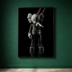 May include: A framed wall art print featuring a stylized black and white character figure with X-shaped eyes. The figure has a split-tone head, metallic silver hands, and two thin orange light beams emanating from the eyes against a solid black background.
