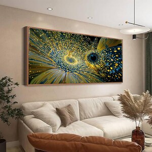 May include: A rectangular wall art piece featuring an abstract explosion of gold and blue light particles. The composition displays a central radiating pattern with deep blue tones and bright yellow specks, framed in a thin metallic border.